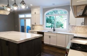 Whole house remodel - kitchen with white cabinets and marble island