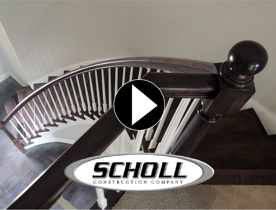 view from top of curved staircase with dark brown banister and spindles